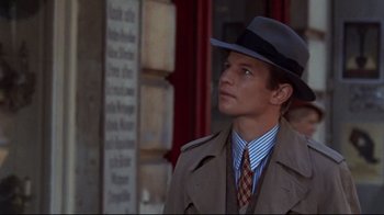 Movie still from “Cabaret” (1972), directed by Bob Fosse – A man wearing a hat and a coat; Close Up shot, Over the shoulder angle