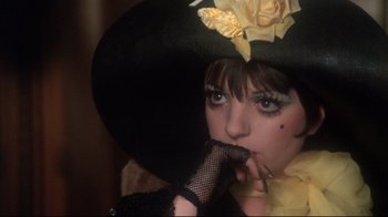 Movie still from “Cabaret” (1972), directed by Bob Fosse – A woman in a black hat and a yellow dress; Close Up shot, High angle
