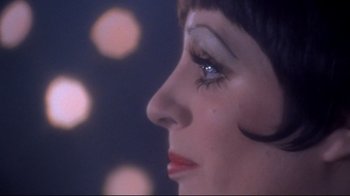 Movie still from “Cabaret” (1972), directed by Bob Fosse – A woman's face with lights in the background; Extreme Close Up shot, Over the shoulder angle