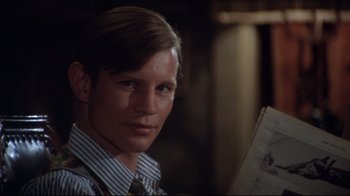 Movie still from “Cabaret” (1972), directed by Bob Fosse – A man in a tie holding a newspaper in front of a window; Close Up shot, Over the shoulder angle