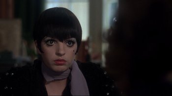 Movie still from “Cabaret” (1972), directed by Bob Fosse – A person with short black hair; Close Up shot, Over the shoulder angle