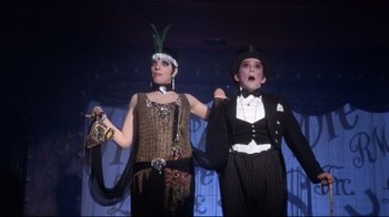 Movie still from “Cabaret” (1972), directed by Bob Fosse – A couple of people that are standing up in a room; Medium shot, Low angle
