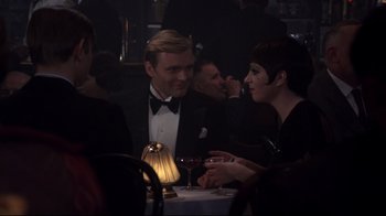 Movie still from “Cabaret” (1972), directed by Bob Fosse – A group of people sitting at a table with wine glasses; Medium shot, Over the shoulder angle