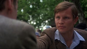 Movie still from “Cabaret” (1972), directed by Bob Fosse – A man in a brown jacket is sitting in a park; Close Up shot, Over the shoulder angle