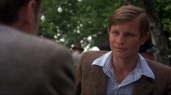 Movie still from “Cabaret” (1972), directed by Bob Fosse – A man in a brown jacket and a striped shirt; Close Up shot, Over the shoulder angle