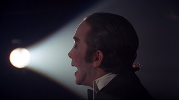 Movie still from “Cabaret” (1972), directed by Bob Fosse – A person wearing a suit and tie; Close Up shot, Low angle