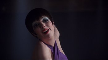 Movie still from “Cabaret” (1972), directed by Bob Fosse – A woman in a purple dress posing for a picture; Close Up shot, Over the shoulder angle