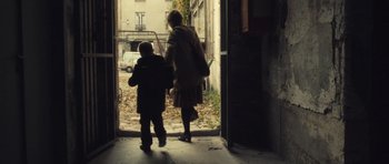Movie still from “Café de Flore” (2011), directed by Jean-Marc Vallée – A woman and a child are walking through a door way; Wide shot, Over the shoulder angle