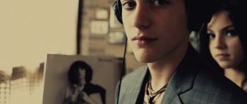 Movie still from “Café de Flore” (2011), directed by Jean-Marc Vallée – A young man wearing headphones in front of a picture; Close Up shot, Overhead angle