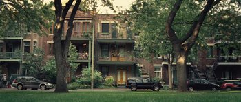 Movie still from “Café de Flore” (2011), directed by Jean-Marc Vallée – A car parked on the side of the road in front of an apartment building; Extreme Wide shot, High angle