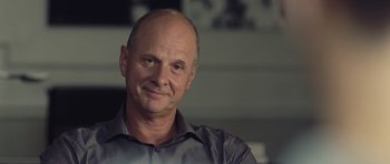 Movie still from “Café de Flore” (2011), directed by Jean-Marc Vallée – A man with a shaved head is posing for a picture; Close Up shot, Over the shoulder angle