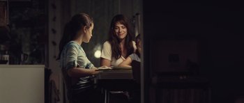 Movie still from “Café de Flore” (2011), directed by Jean-Marc Vallée – Two women are sitting at a table and one is reading a book; Medium shot, Over the shoulder angle
