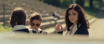 Movie still from “Café de Flore” (2011), directed by Jean-Marc Vallée – Two women are sitting in a stadium and one of them is smoking a cigarette; Medium shot, Over the shoulder angle