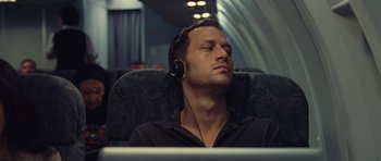 Movie still from “Café de Flore” (2011), directed by Jean-Marc Vallée – A man is listening to music while sitting on a plane; Close Up shot, Low angle