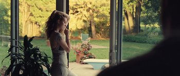 Movie still from “Café de Flore” (2011), directed by Jean-Marc Vallée – A woman sitting on a porch looking out a sliding glass door; Medium shot, Over the shoulder angle