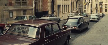 Movie still from “Café de Flore” (2011), directed by Jean-Marc Vallée – A group of cars driving down a street next to tall buildings; Wide shot, High angle