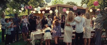 Movie still from “Café de Flore” (2011), directed by Jean-Marc Vallée – A group of people standing around a table with food; Wide shot, Over the shoulder angle