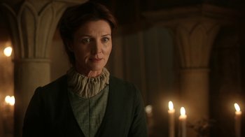 Movie still from “Game of Thrones” (2011), created by D.B. Weiss – A woman standing in front of candles in a dimly - lit room; Close Up shot, Low angle