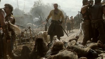 Movie still from “Game of Thrones” (2011), created by D.B. Weiss – A group of people standing next to dead bodies; Wide shot, Over the shoulder angle