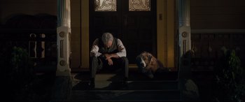 Movie still from “The Call of the Wild” (2020), directed by Chris Sanders – An older man sitting on the steps next to a dog; Wide shot, Low angle