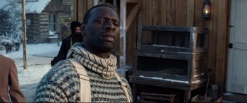 Movie still from “The Call of the Wild” (2020), directed by Chris Sanders – A man wearing a scarf standing in front of a wooden building; Close Up shot, Over the shoulder angle