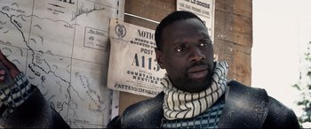 Movie still from “The Call of the Wild” (2020), directed by Chris Sanders – A man wearing a scarf standing in front of a sign; Close Up shot, Over the shoulder angle