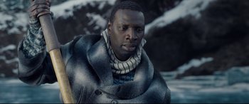 Movie still from “The Call of the Wild” (2020), directed by Chris Sanders – A man wearing a jacket and a scarf is standing in front of a body of water; Close Up shot, Over the shoulder angle
