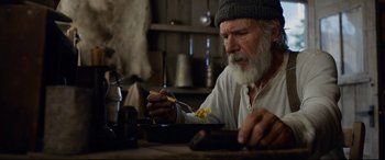 Movie still from “The Call of the Wild” (2020), directed by Chris Sanders – An old man sitting at a table eating food; Medium shot, Low angle