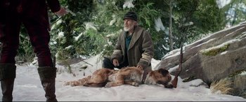 Movie still from “The Call of the Wild” (2020), directed by Chris Sanders – An old man sitting on the ground next to a dog; Wide shot, High angle