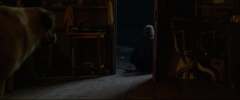 Movie still from “The Call of the Wild” (2020), directed by Chris Sanders – An old man sitting on the floor in front of an open door; Wide shot, High angle