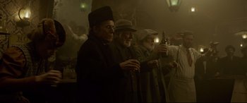 Movie still from “The Call of the Wild” (2020), directed by Chris Sanders – A group of men standing next to each other holding drinks; Medium shot, Low angle