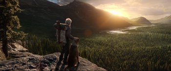 Movie still from “The Call of the Wild” (2020), directed by Chris Sanders – A man standing on top of a mountain next to a dog; Wide shot, Low angle