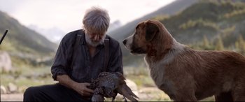 Movie still from “The Call of the Wild” (2020), directed by Chris Sanders – An old man holding a bird next to a dog; Medium shot, Low angle
