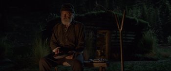 Movie still from “The Call of the Wild” (2020), directed by Chris Sanders – An old man sitting on a bench in the dark; Medium shot, Over the shoulder angle