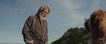 Movie still from “The Call of the Wild” (2020), directed by Chris Sanders – An old man with a beard is standing in front of a hill; Medium shot, Low angle