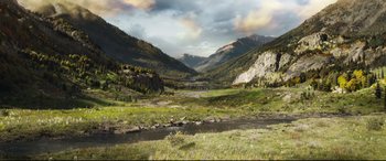 Movie still from “The Call of the Wild” (2020), directed by Chris Sanders – A river running through a lush green valley; Extreme Wide shot, High angle