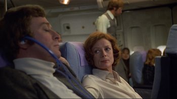 Movie still from “California Suite” (1978), directed by Herbert Ross – A man and a woman sitting on a seat on an airplane; Medium shot, Over the shoulder angle