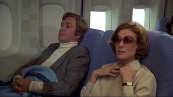 Movie still from “California Suite” (1978), directed by Herbert Ross – A man and a woman sitting next to each other on an airplane; Medium shot, Low angle