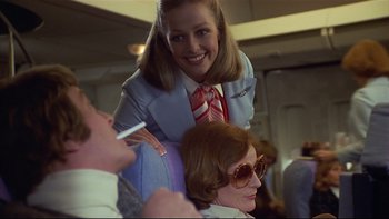Movie still from “California Suite” (1978), directed by Herbert Ross – An airline stewardess sitting next to an older woman; Medium shot, Over the shoulder angle