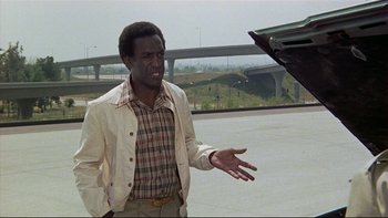 Movie still from “California Suite” (1978), directed by Herbert Ross – A man in a plaid shirt and a white jacket; Medium shot, Over the shoulder angle
