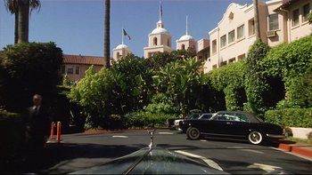 Movie still from “California Suite” (1978), directed by Herbert Ross – A view from a car window of a building with a car parked in front of it; Wide shot, Low angle