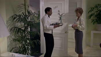 Movie still from “California Suite” (1978), directed by Herbert Ross – A man holding a tray of food in front of a woman in front of a door; Wide shot, High angle