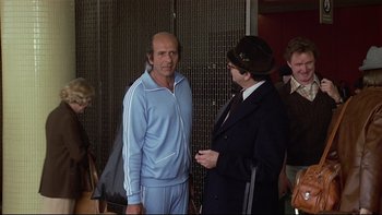 Movie still from “California Suite” (1978), directed by Herbert Ross – A man in a suit talks to another man in a suit; Medium shot, Over the shoulder angle