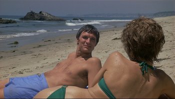 Movie still from “California Suite” (1978), directed by Herbert Ross – A man and a woman sitting on the beach; Medium shot, Low angle