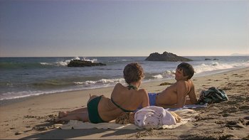 Movie still from “California Suite” (1978), directed by Herbert Ross – A man and a woman sitting on the beach; Wide shot, High angle