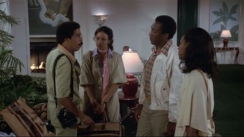 Movie still from “California Suite” (1978), directed by Herbert Ross – A group of people standing around each other in a room; Medium shot, High angle