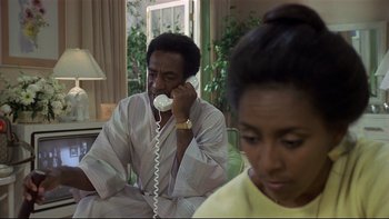 Movie still from “California Suite” (1978), directed by Herbert Ross – A man and a woman sitting in a living room talking on a phone; Medium shot, High angle