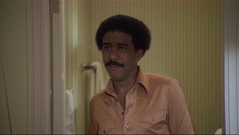 Movie still from “California Suite” (1978), directed by Herbert Ross – A man in a tan shirt is standing in a bathroom; Close Up shot, Low angle