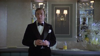 Movie still from “California Suite” (1978), directed by Herbert Ross – A man in a tuxedo holding a wine glass in his hand; Medium shot, Low angle