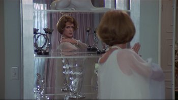 Movie still from “California Suite” (1978), directed by Herbert Ross – A woman is looking in the mirror in front of a table; Medium shot, Over the shoulder angle